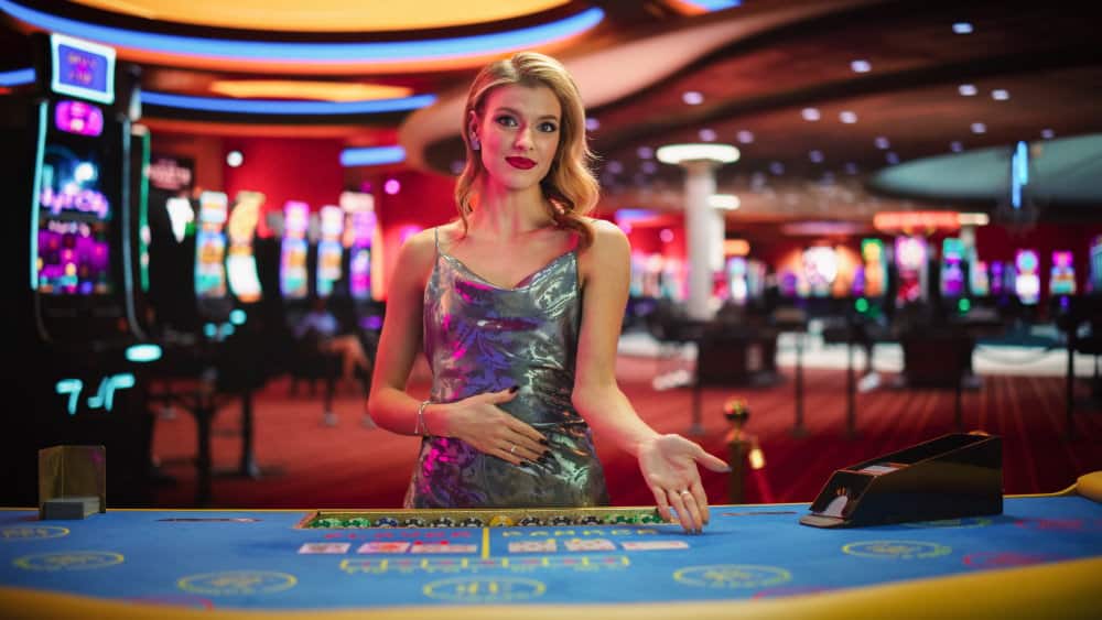 A female casino dealer inviting you to have a seat